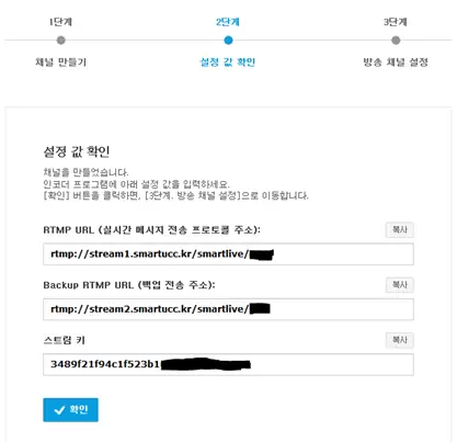 Screenshot of step 2 in a live streaming channel setup process. The screen shows RTMP and backup RTMP stream URLs provided by smartucc.kr, along with a unique stream key. Users are instructed to copy and use these URLs and the stream key in their encoder software for live broadcasting. A blue 'Confirm' button appears at the bottom.